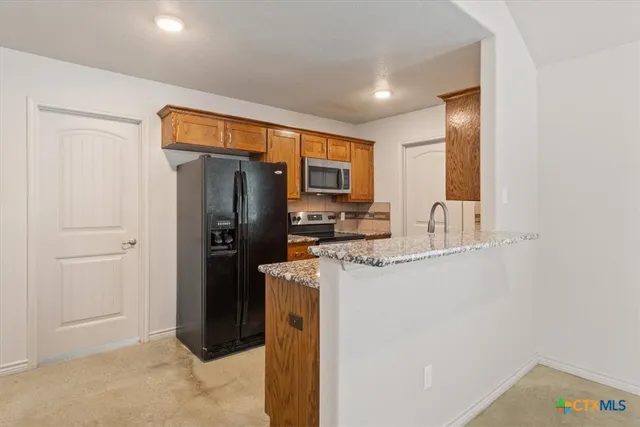 a kitchen with stainless steel appliances granite countertop a refrigerator and a sink
