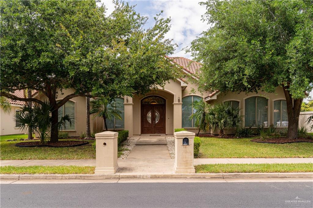 a front view of a house with garden and trees