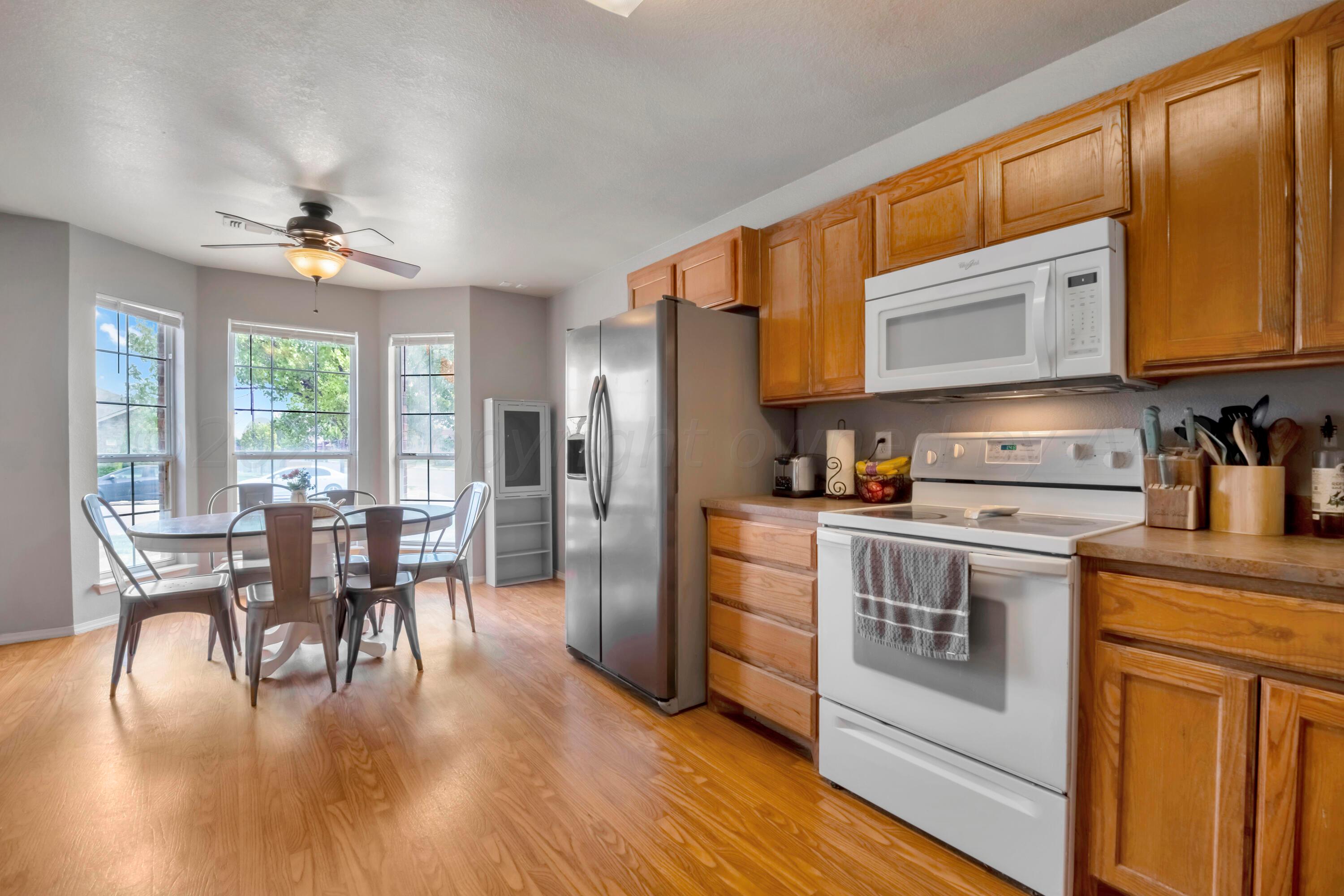 4902 Capulin Lane Amarillo, TX 79110 - Photo 1 of 25 a kitchen with stainless steel appliances granite countertop a stove top oven a refrigerator a dining table and chairs with wooden floor