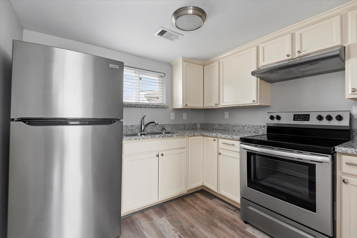 7413 Dallas Street Houston, TX 77011 - Photo 14 of 26 a kitchen with stainless steel appliances granite countertop a refrigerator a stove a sink and dishwasher with wooden floor