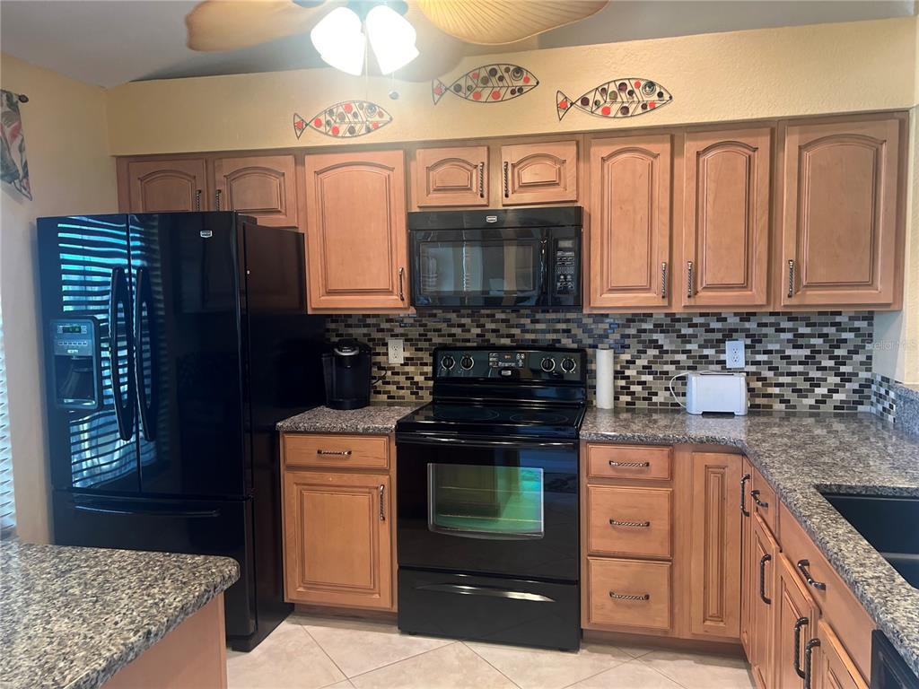 220 Coldeway Drive, Unit 123 Punta Gorda, FL 33950 - Photo 4 of 59 a kitchen with granite countertop a stove top oven microwave and cabinets