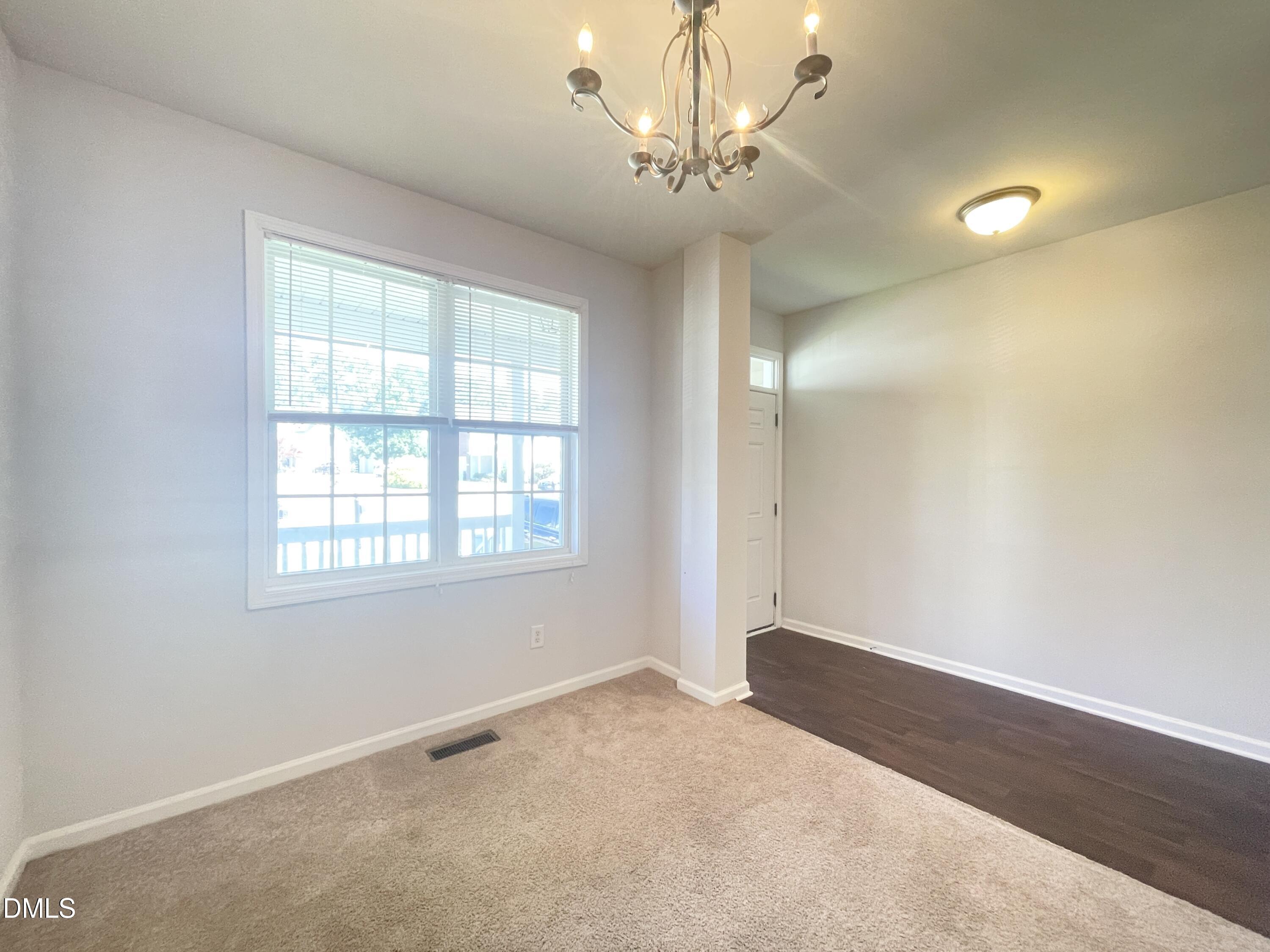 112 Taylors Creek Court Raleigh, NC 27610 - Photo 7 of 34 an empty room with a chandelier fan and windows