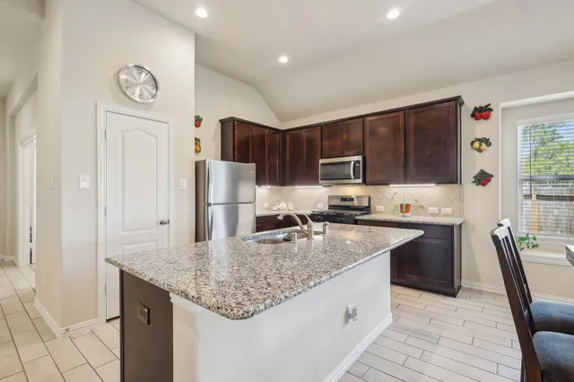 a kitchen with granite countertop a sink a counter space appliances and cabinets