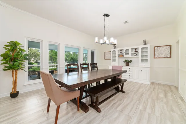 a dining room with wooden floor a chandelier a glass table and chairs
