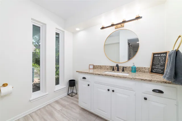 a bathroom with a granite countertop double vanity sink and a mirror