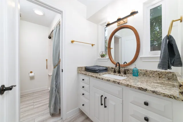 a bathroom with a granite countertop sink and a mirror