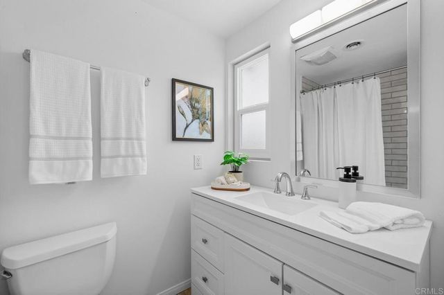 a bathroom with a granite countertop sink a toilet and mirror