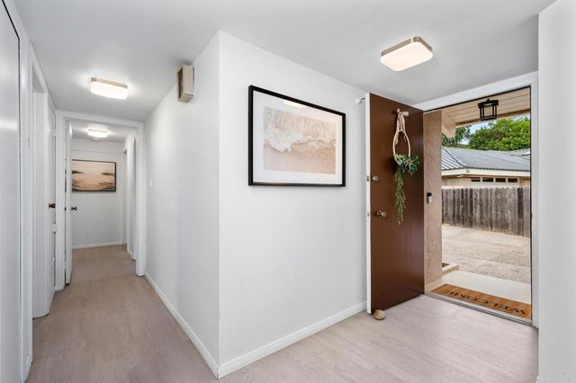 a view of a hallway with wooden floor and a bathroom