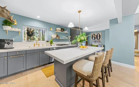 a kitchen with a sink a counter top space and living room view