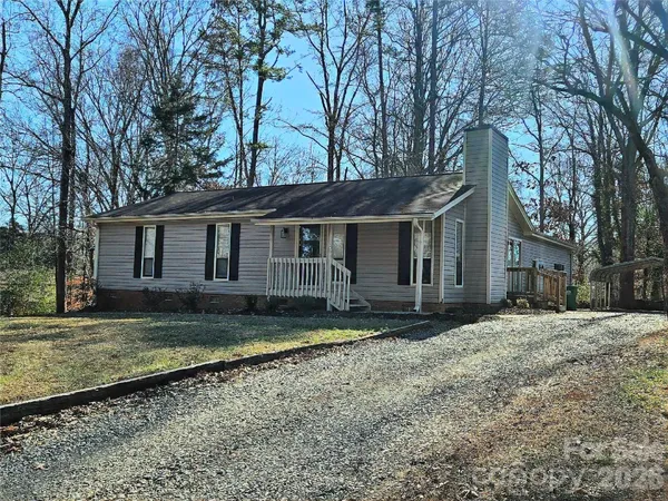 a view of a house with a yard covered with large trees