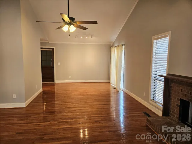 an empty room with wooden floor a ceiling fan and windows