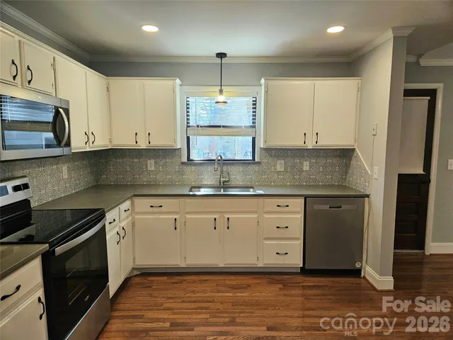 a kitchen with stainless steel appliances granite countertop a stove a sink and white cabinets