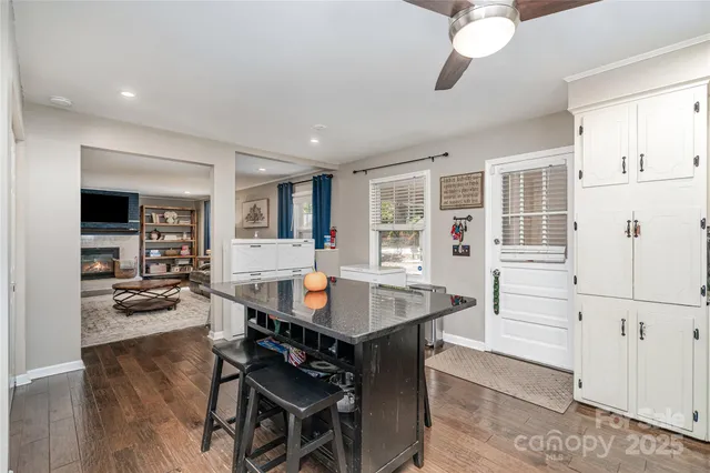 a room with stainless steel appliances kitchen island granite countertop a table chairs in it and wooden floors