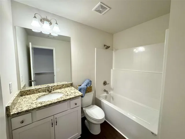 a bathroom with a granite countertop sink a toilet and bathtub