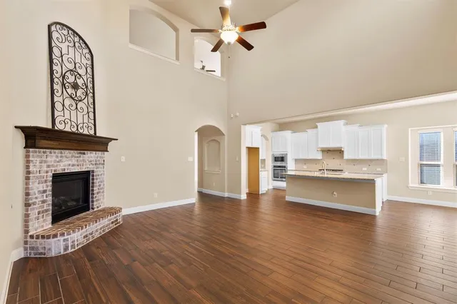 a view of an empty room with kitchen and fireplace
