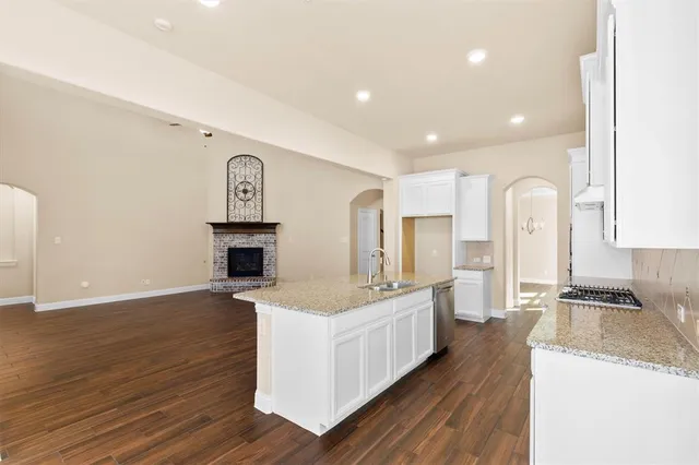 a large kitchen with stainless steel appliances granite countertop a lot of counter space and wooden floor