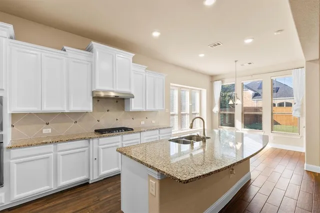 a kitchen with granite countertop a sink a counter top space and cabinets