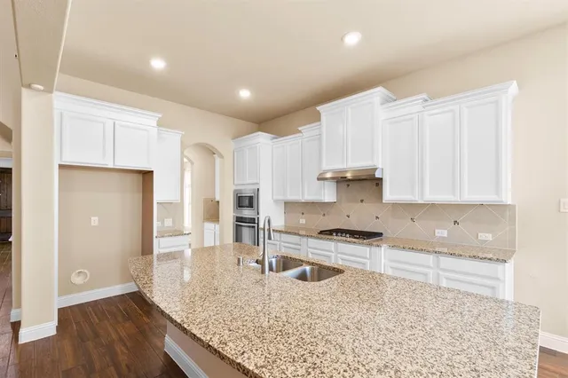 a kitchen with stainless steel appliances granite countertop a sink refrigerator and cabinets