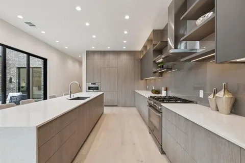 a large kitchen with stainless steel appliances granite countertop a sink a stove and a refrigerator