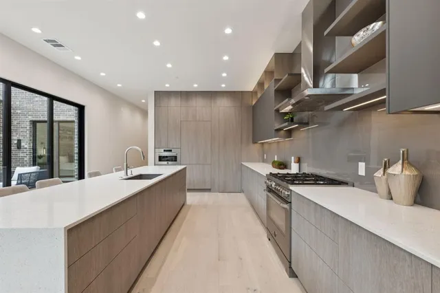 a large kitchen with stainless steel appliances granite countertop a sink a stove and a refrigerator