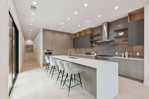 a kitchen with stainless steel appliances granite countertop a sink a stove a refrigerator and island with wooden floor