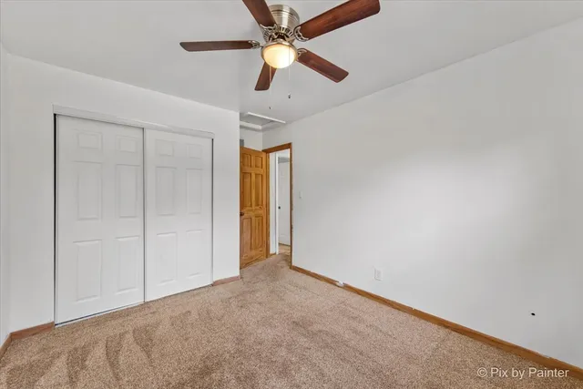 an empty room with closet and a chandelier fan
