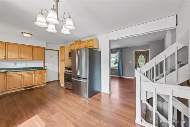 a kitchen with stainless steel appliances granite countertop a refrigerator a stove and a wooden floors