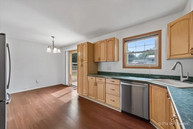 a kitchen with stainless steel appliances granite countertop a sink cabinets and wooden floor