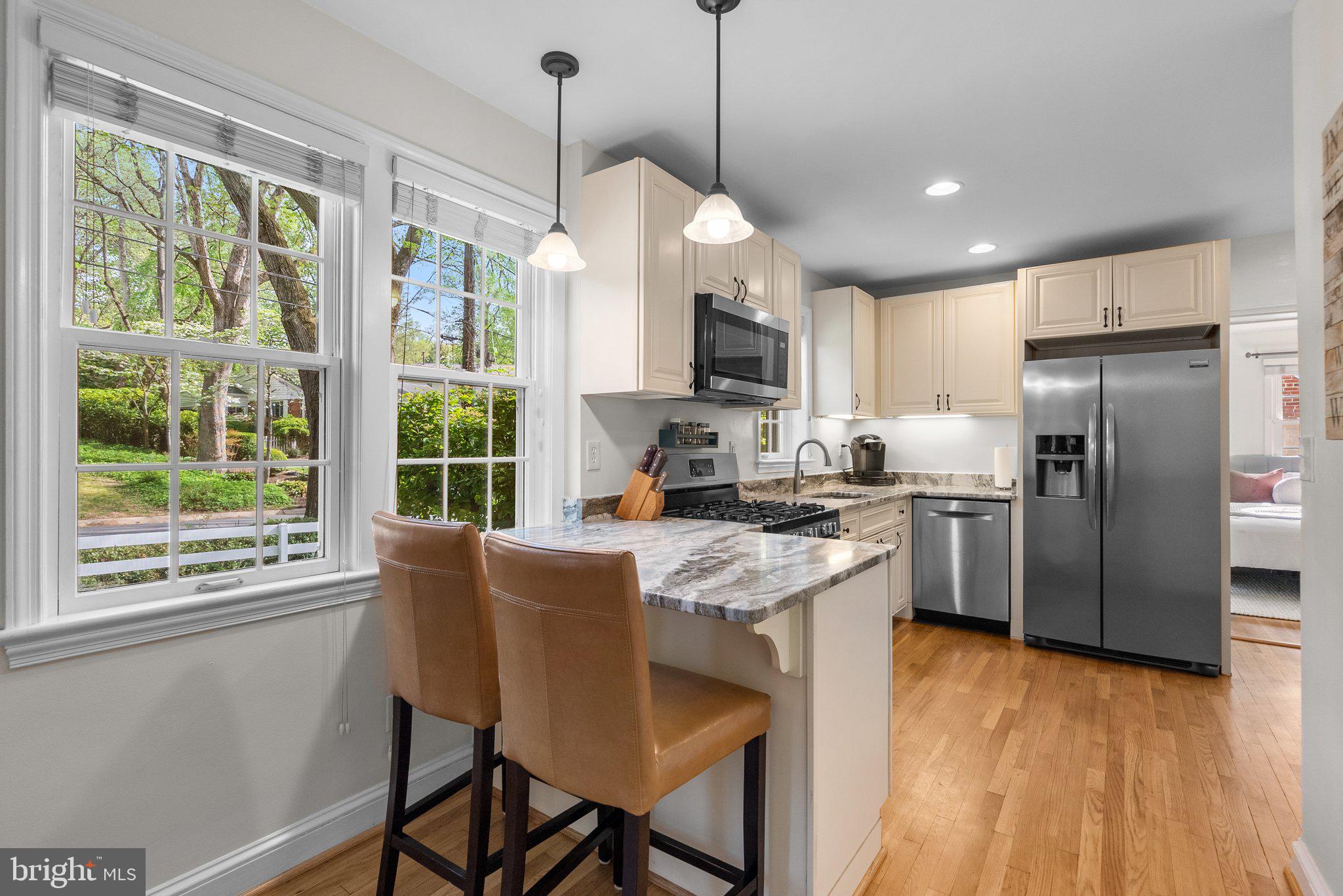 10406 Brookmoor Drive Silver Spring, MD 20901 - Photo 9 of 45 a kitchen with stainless steel appliances granite countertop a refrigerator a sink dishwasher a stove and a dining table with wooden floor