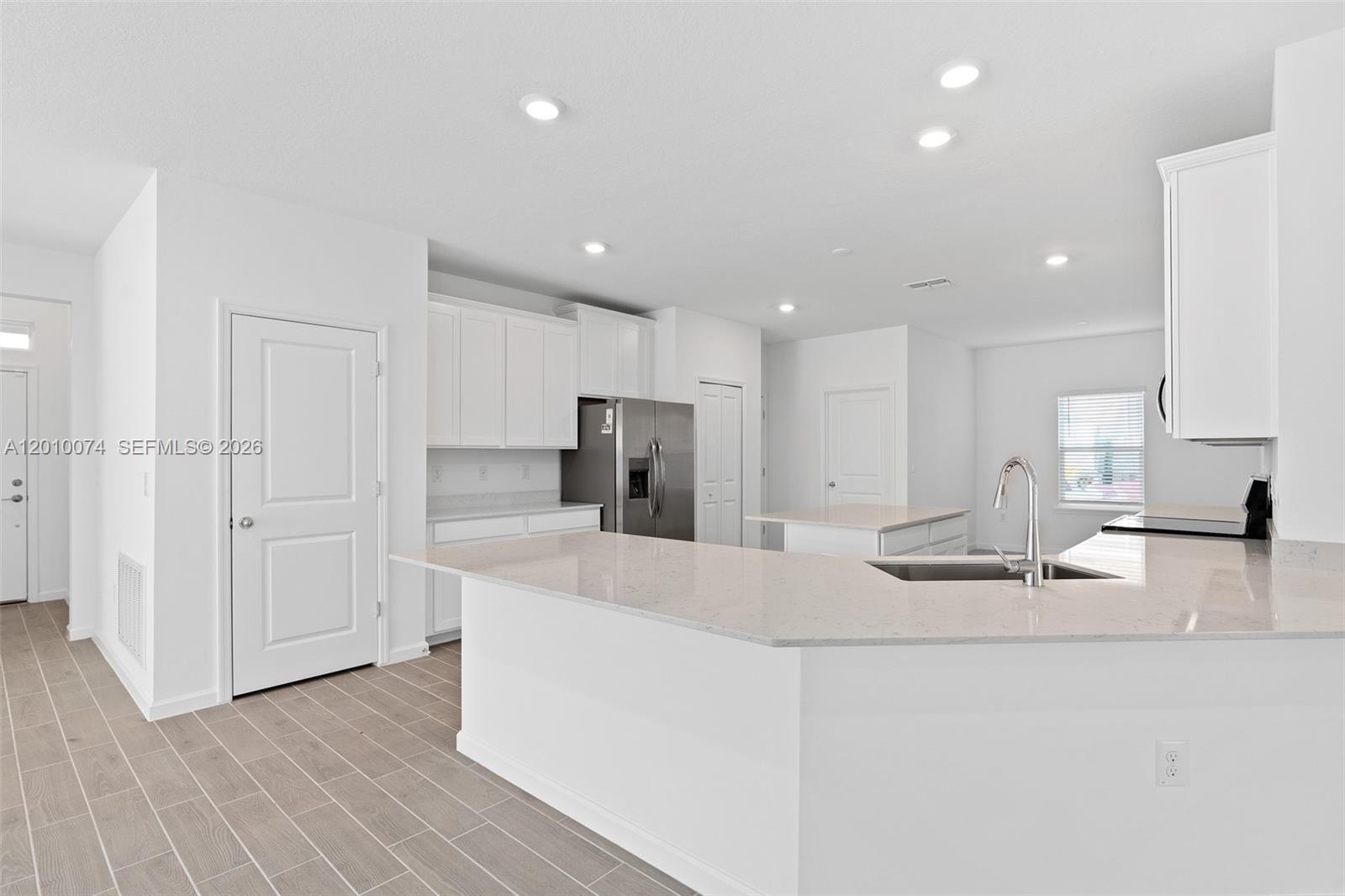 7789 Southwest 196th Terrace, Unit 1 Dunnellon, FL 34432 - Photo 13 of 36 a large kitchen with kitchen island a sink a stove a refrigerator and white cabinets