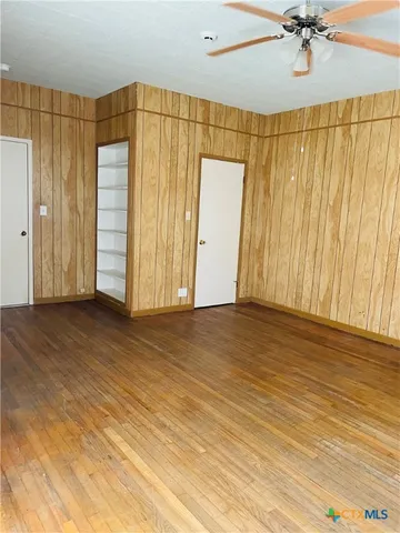 a view of a room with wooden floor and a ceiling fan