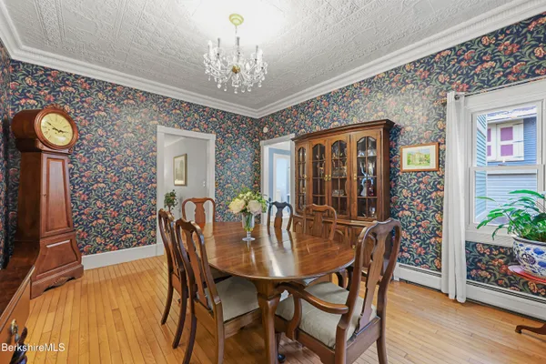 a kitchen with stainless steel appliances kitchen island granite countertop a refrigerator a stove a sink a dining table and chairs with wooden floor