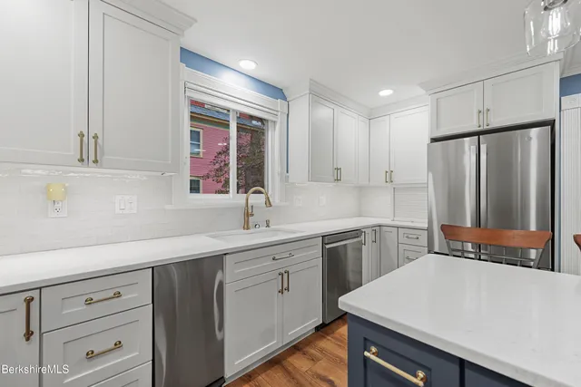 a kitchen with kitchen island white cabinets and stainless steel appliances