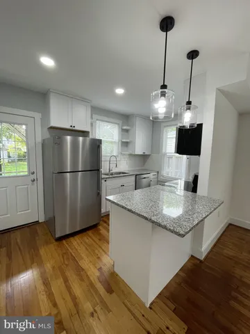 a kitchen with stainless steel appliances granite countertop a refrigerator a sink dishwasher a stove and a wooden floor