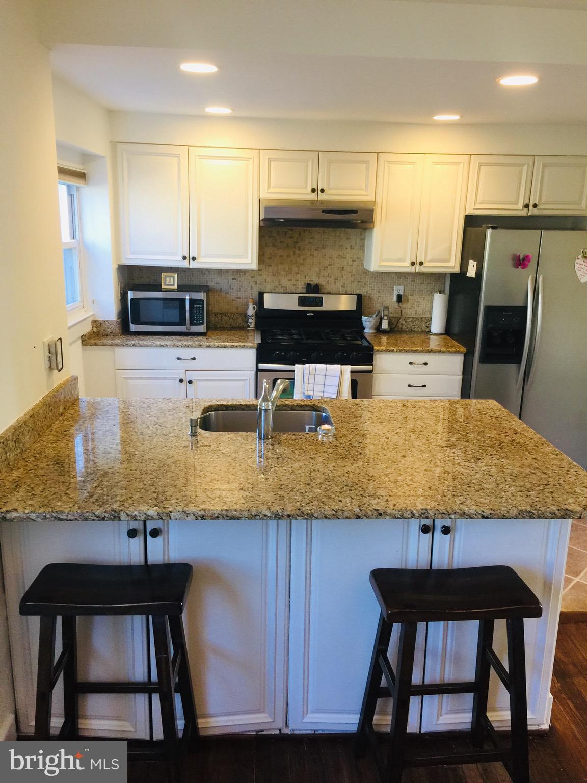 5203 Falls Road, Unit 16 Baltimore, MD 21210 - Photo 8 of 25 a kitchen with granite countertop a table chairs microwave and cabinets