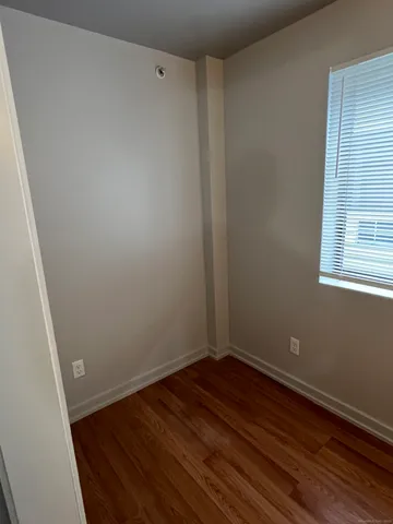 a view of a room with wooden floor and small window