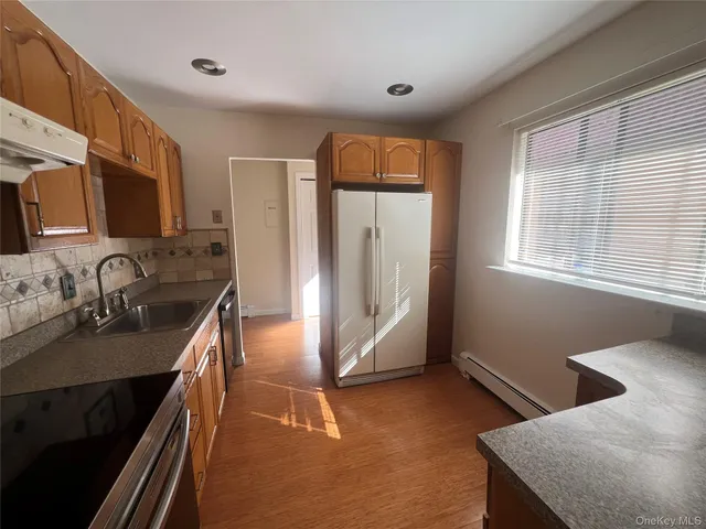 a view of a refrigerator in kitchen and an empty room
