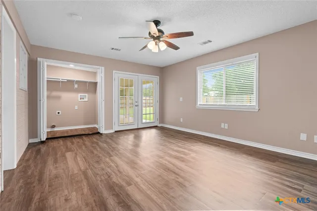 a view of an empty room with wooden floor and a window