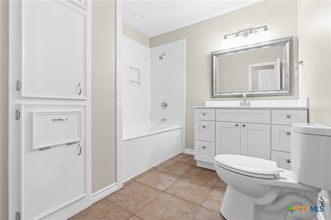 607 South Nancy Ann Street Hamilton, TX 76531 - Photo 19 of 26 a bathroom with a toilet a sink and a mirror