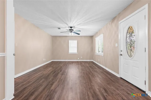 an empty room with windows and fan