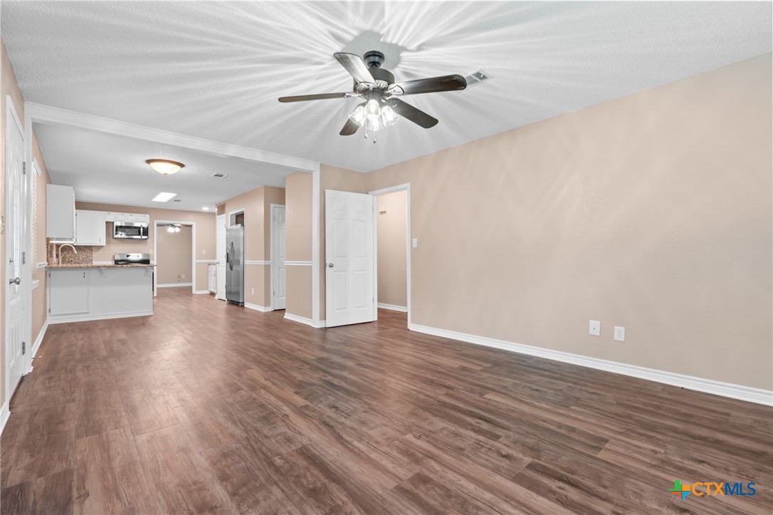 607 South Nancy Ann Street Hamilton, TX 76531 - Photo 6 of 26 a view of an empty room with wooden floor and a ceiling fan