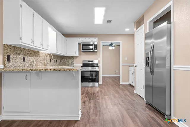 a kitchen with stainless steel appliances granite countertop a refrigerator a stove and a sink