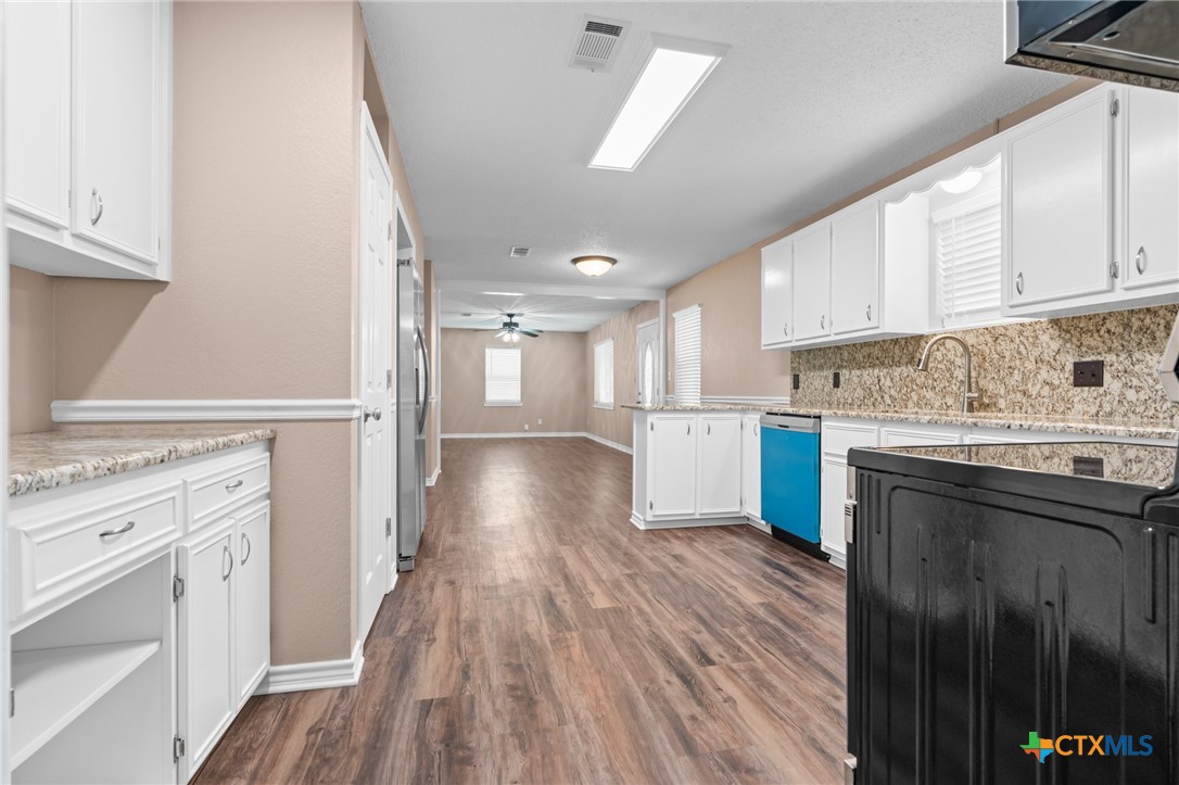 607 South Nancy Ann Street Hamilton, TX 76531 - Photo 9 of 26 a kitchen with granite countertop a stove top oven a sink dishwasher and a refrigerator with wooden floor