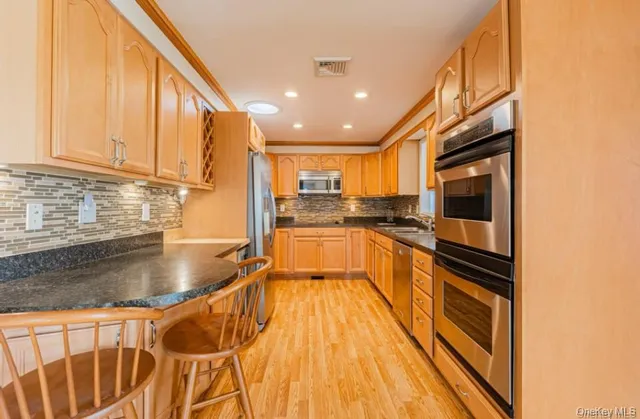 a kitchen with stainless steel appliances granite countertop a stove a sink and a microwave
