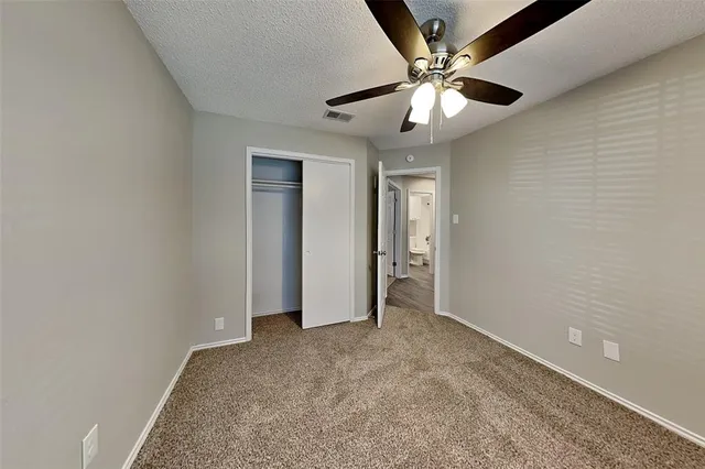 an empty room with closet and a ceiling fan