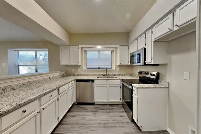 a kitchen with stainless steel appliances granite countertop a sink and dishwasher a stove top oven with wooden floor