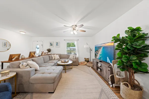 a living room with furniture a potted plant and a flat screen tv