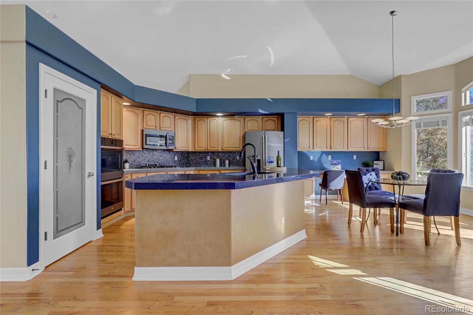 13810 Muirfield Circle Broomfield, CO 80023 - Photo 14 of 45 a kitchen with stainless steel appliances granite countertop a stove top oven a sink dishwasher a dining table and chairs with wooden floor