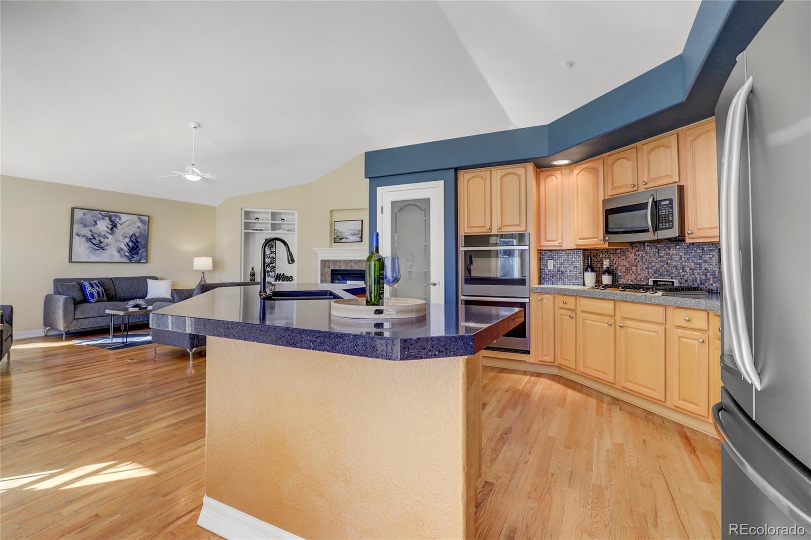 13810 Muirfield Circle Broomfield, CO 80023 - Photo 17 of 45 a large living room with stainless steel appliances granite countertop a refrigerator a stove top oven and a view of living room