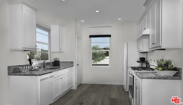 a kitchen with granite countertop a sink a stove and cabinets